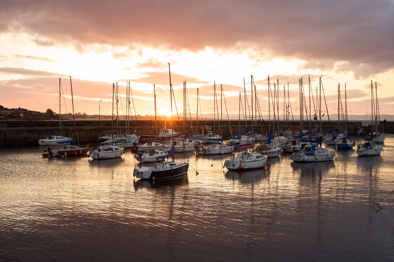Segelboote liegen bei Sonnenuntergang im Hafen.