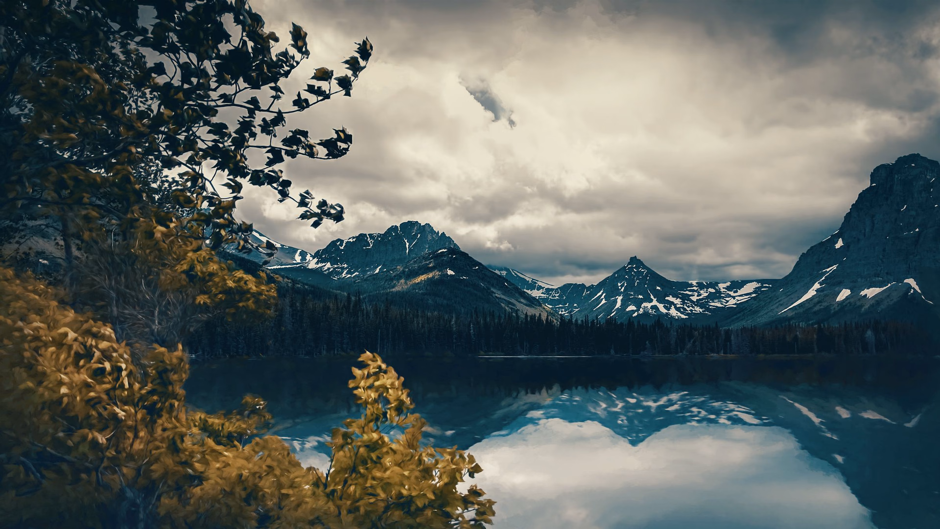 Berge und Wolken spiegeln sich in einem See.