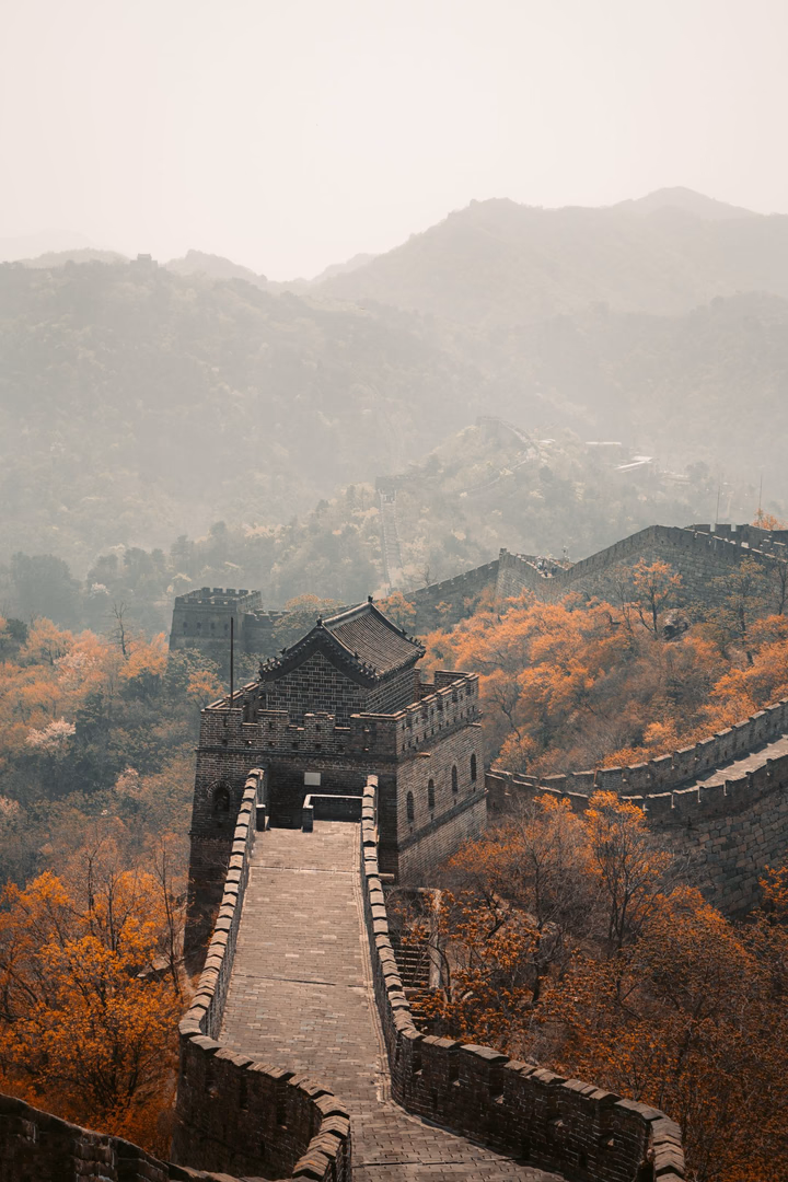 Die Chinesische Mauer zieht sich durch eine herbstliche Berglandschaft.