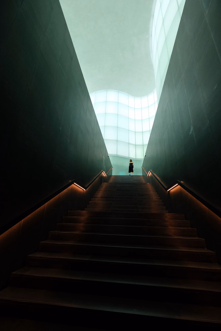 Eine Person steht am oberen Ende einer beleuchteten Treppe.