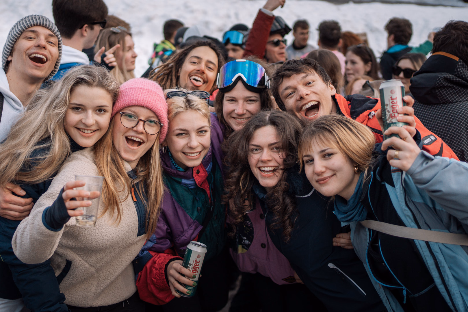 Lachende Freunde beim Après-Ski mit Drinks und bunten Skijacken